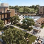 Aerial view of The Livelle's modern courtyard featuring a pool, lounge areas, and trees, surrounded by three-story buildings with large windows and balconies. People are scattered across the area.